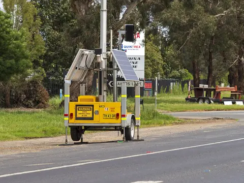 A trailer-mounted mobile phone detection camera beside a highway