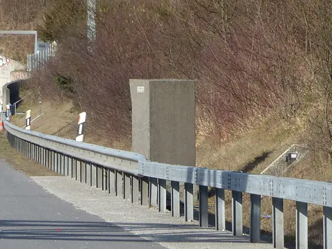 A grey speed camera cabinet beside a motorway near a tunnel