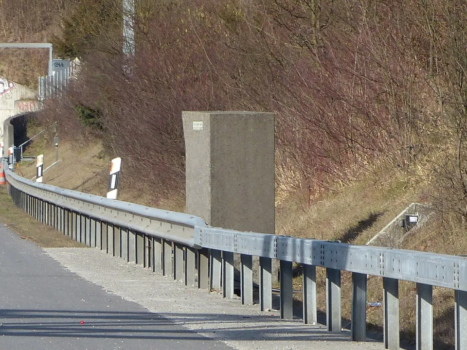 A grey speed camera cabinet beside a motorway near a tunnel