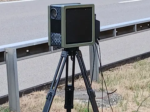 A mobile speed camera on a tripod beside a motorway