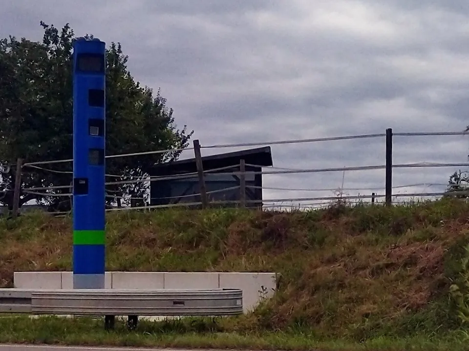 A tall blue toll enforcement column beside a main road