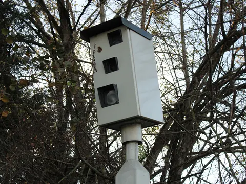 A grey red light camera housing on a post