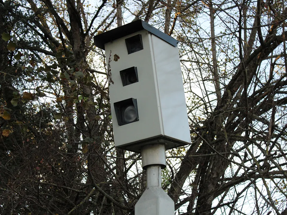 A grey red light camera housing on a post