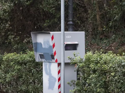 A fixed speed camera box under a sign saying postazione fissa misuratore della velocità