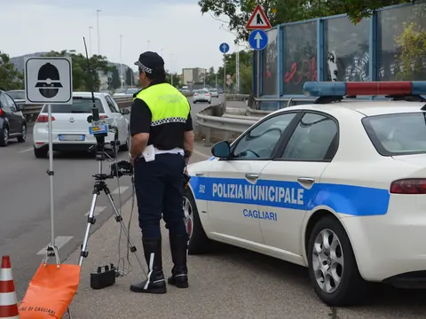 A municipal police officer beside a speed radar on a tripod and a police car