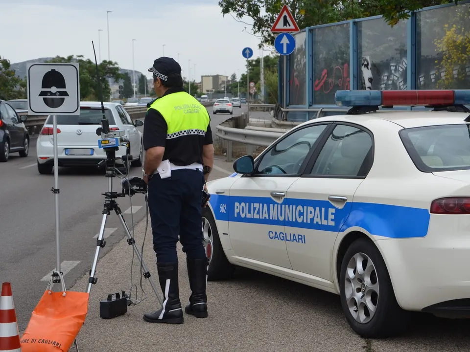 A municipal police officer beside a speed radar on a tripod and a police car