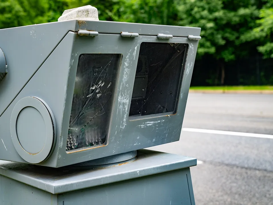 A grey speed camera housing at the side of a road